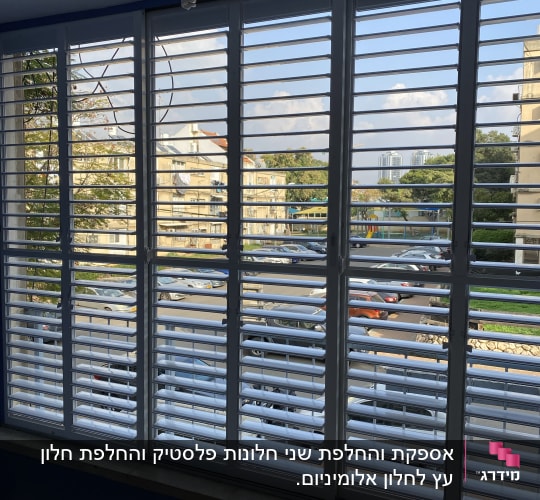 תריסים לבנים על חלון גדול עם נוף עירוני
